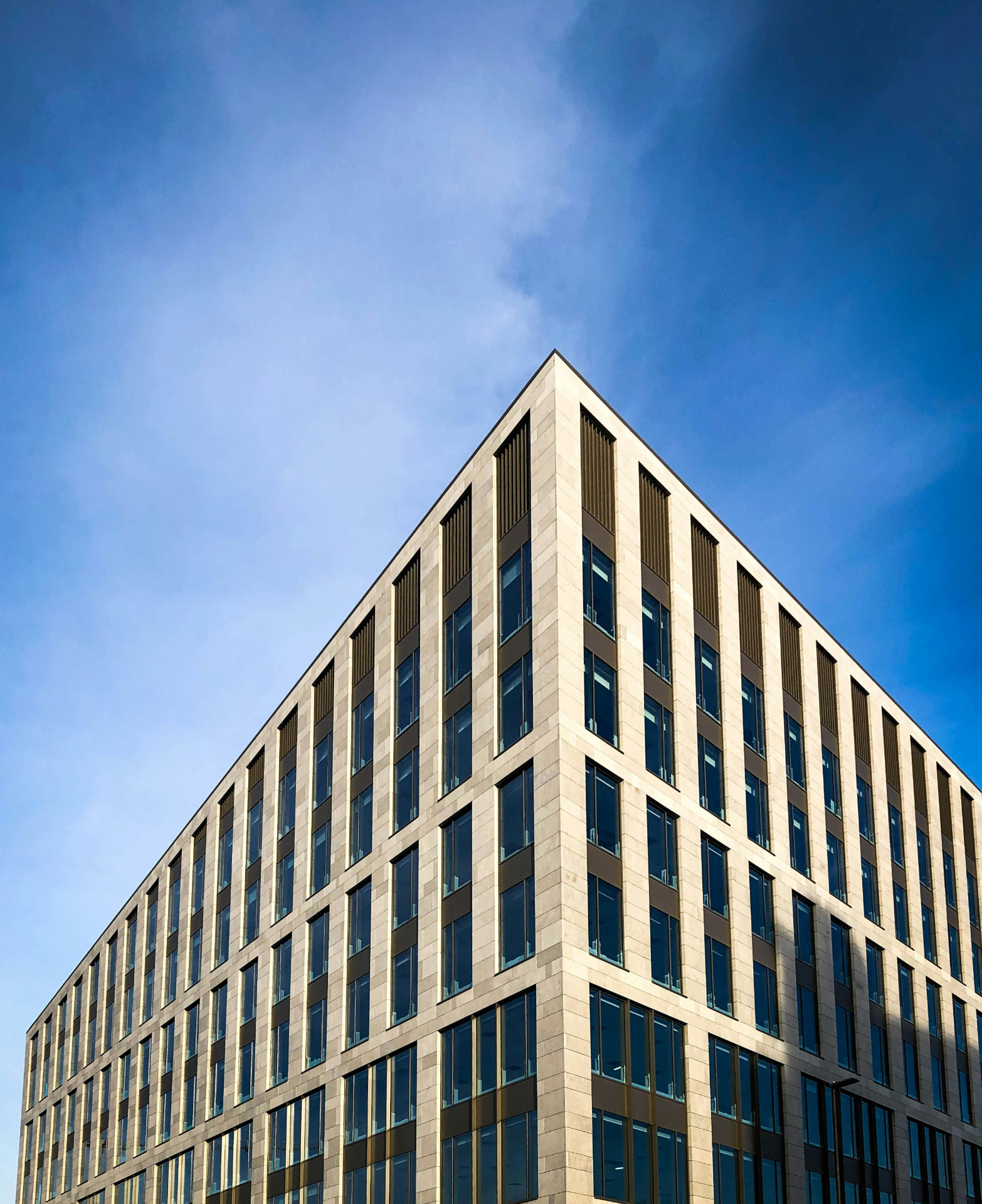 Moderne Bürogebäude-Fassade aus Naturstein vor blauem Himmel